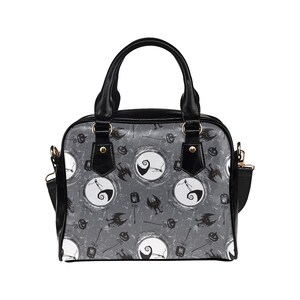 K&ouml;nnte beinhalten: Schwarze Handtasche mit einem grau-wei&szlig;en Muster, das eine Figur aus Nightmare Before Christmas zeigt. Das Muster enth&auml;lt auch Flederm&auml;use, K&uuml;rbisse und einen Mond.