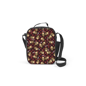 May include: Black lunch bag with a repeating pattern of hockey masks and knives on a red and black background. The bag has a black adjustable shoulder strap.