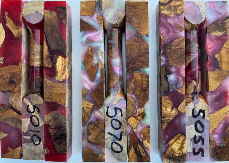 May include: Three rectangular blocks made of natural wood burl and colored resin. The left block features red resin, the center has pink and white swirls, and the right has purple and white swirls. Each block is marked with numbers 5019, 5070, and 5055.