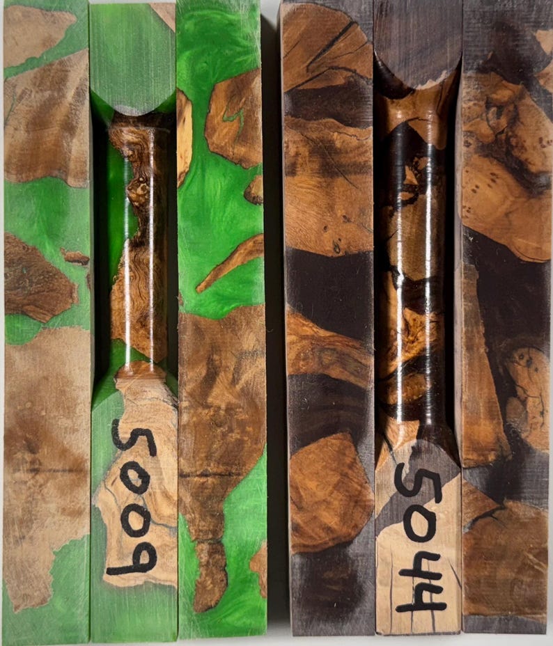 May include: Two rectangular wood and resin turning blanks. The left blank features bright green resin with natural wood burl inclusions and the number 5009. The right blank features dark charcoal resin with natural wood burl inclusions and the number 5044.