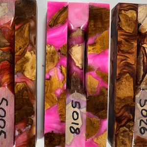 May include: Three rectangular blocks made of wood burl and resin. The left block features orange and brown resin, the center block has bright pink resin, and the right block contains dark brown resin. Each block is marked with the numbers 5005, 5018, or 5026.
