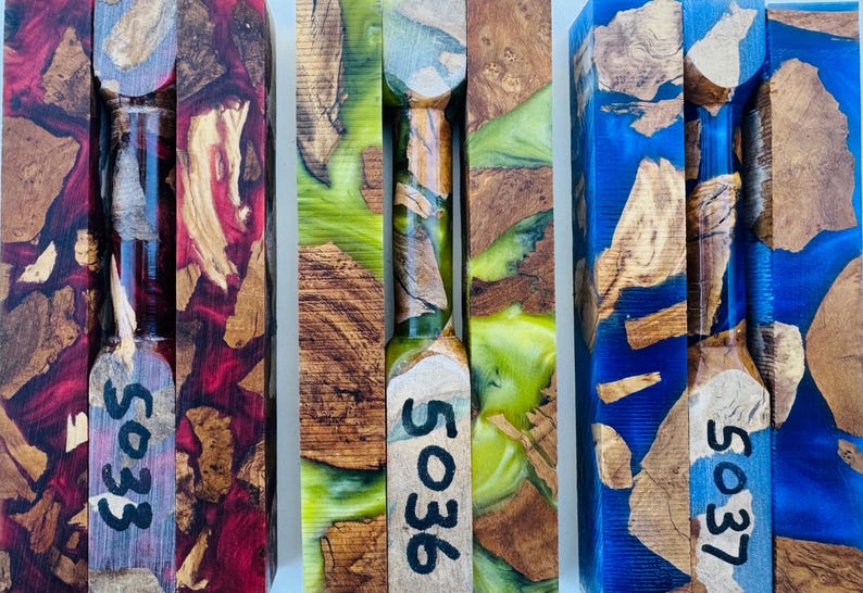 May include: Three rectangular wood and resin turning blanks featuring natural wood burl inclusions suspended in vibrant red, lime green, and blue translucent resin. Each blank is marked with black handwritten numbers 5033, 5036, and 5037.