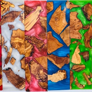 May include: A collection of colorful epoxy resin and wood pieces. Each piece features a unique combination of wood grain and vibrant resin colors, including red, white, blue, and green. The wood pieces are irregularly shaped and embedded in the resin.