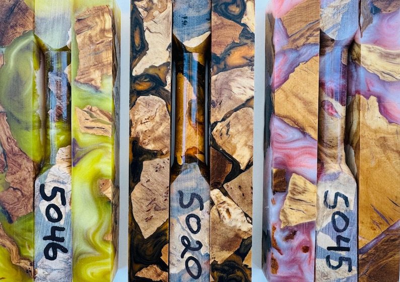 May include: Three rectangular blocks made of natural wood burl and colored resin. The left block features bright yellow resin, the center block has dark brown resin, and the right block contains pink resin. Each block is marked with numbers 5046, 5020, and 5045.