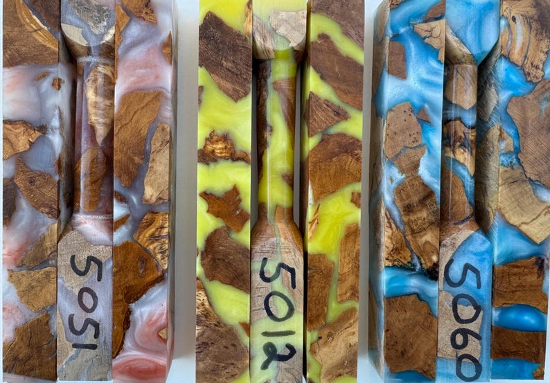 May include: Three rectangular blocks of burl wood encased in colored resin. The left block features pinkish-white resin and is marked 5051. The center block has bright yellow resin and is marked 5012. The right block has blue resin and is marked 5060.