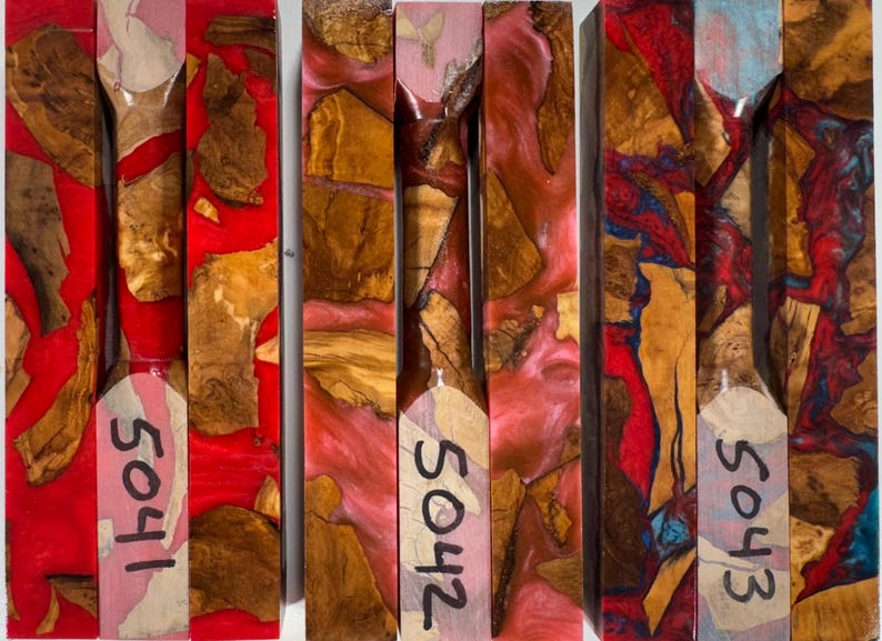 May include: Three rectangular blocks of wood and resin composite. The first block is marked 5041 with red resin, the second is marked 5042 with pink resin, and the third is marked 5043 with blue and red resin. Each block features natural wood burl pieces.