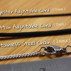 May include: Close-up of three different types of necklace cords: polyester adjustable cord (1mm), cotton adjustable cord (2mm), and stainless steel chain (2mm x 1mm).