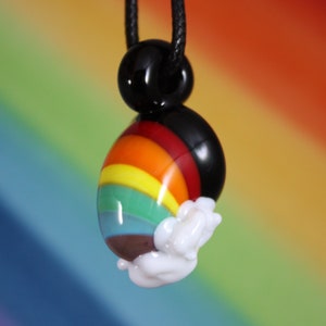 May include: A rainbow glass pendant with a white cloud design, hanging from a black cord.