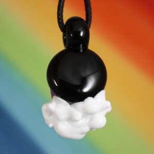 May include: A black glass pendant with a white glass cloud design. The pendant is hanging from a black cord.