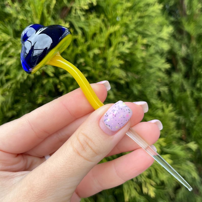 May include: A glass mushroom with a blue and yellow cap and a clear stem.