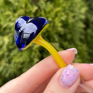 May include: A glass mushroom figurine with a blue cap and a yellow stem.