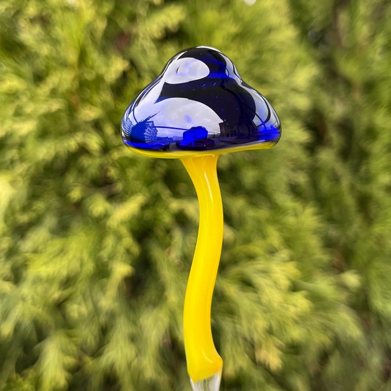 May include: A glass mushroom garden stake with a blue cap and a yellow stem.