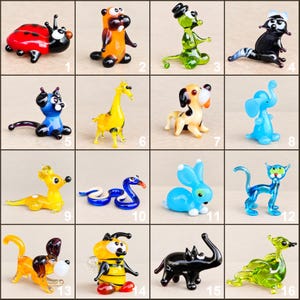 May include: A collection of sixteen miniature glass animal figurines, including a ladybird, beaver, green creature, raccoon, cat, giraffe, dog, elephant, yellow animal, snake, blue rabbit, blue cat, orange dog, bee, black elephant, and green bird.