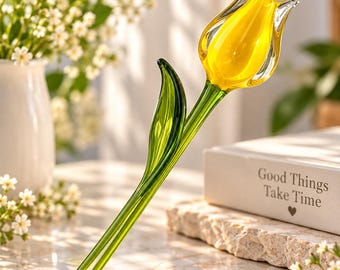 Könnte beinhalten: Eine Tulpenskulptur aus Glas mit einem leuchtend gelben Blütenkopf mit klaren Glasrändern sowie einem glatten, durchscheinenden grünen Stiel und Blatt. Das Stück ist glänzend verarbeitet und zeigt eine realistische florale Form.