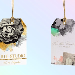 May include: Two white gift tags with gold accents and floral designs. The tag on the left features a black and white rose with gold paint splatters. The tag on the right features a black and white floral design with green and pink paint splatters. Both tags have the text "LILLE STUDIO Los Angeles" printed on them.