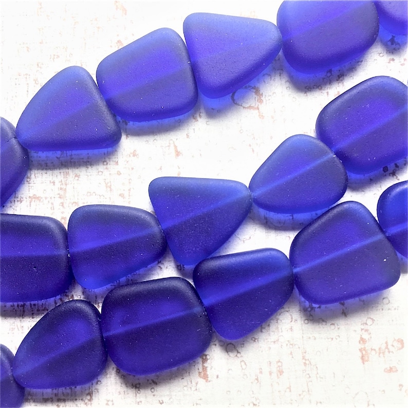 K&ouml;nnte beinhalten: Eine Str&auml;hne blauer Glasperlen in Tropfenform. Die Perlen sind matt und haben eine durchscheinende Optik.