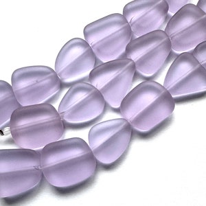 May include: A strand of lavender-coloured glass beads, each bead is a smooth, rounded, and slightly irregular shape.