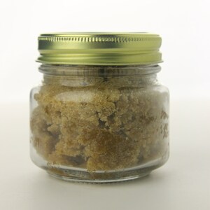May include: A glass jar with a gold lid filled with brown sugar crystals.