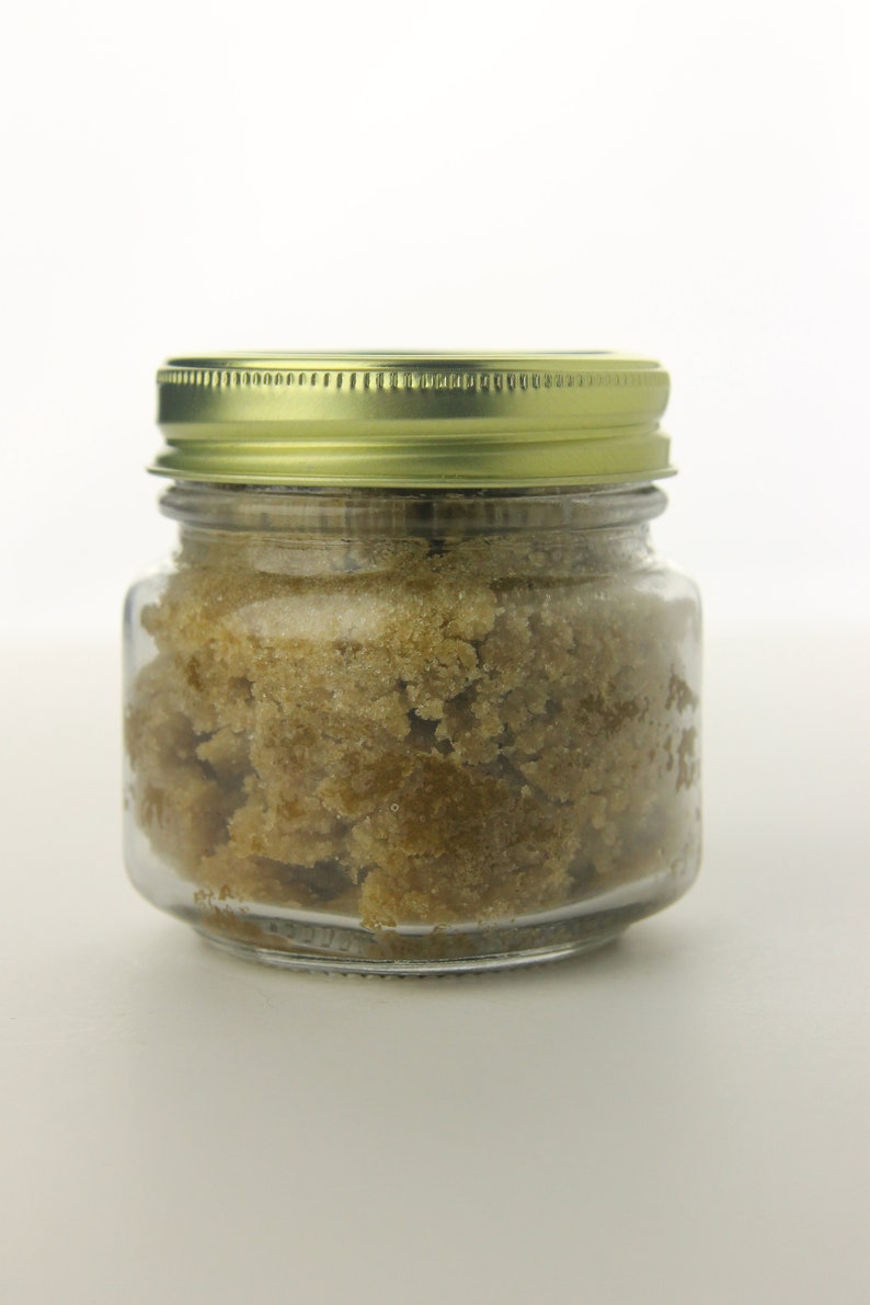May include: A glass jar with a gold lid filled with brown sugar crystals.