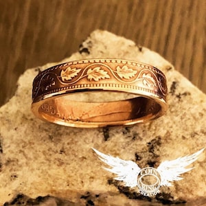 May include: A copper coin ring with a design of leaves and a vine. The ring is made from a genuine coin and is a unique piece of jewelry.