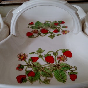 以下が含まれることがあります： ハンドル付きの白いセラミック製のサービングトレイで、イチゴのデザインが施されています。トレイには、側面に2つの小さなボウルが付いています。