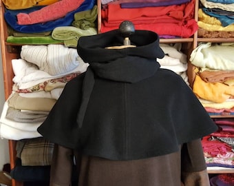 May include: A black hooded cloak with a long, flowing hood. The cloak is made of a soft, warm fabric and has a simple, elegant design.