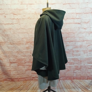 May include: A dark green hooded cape with a long, flowing design. The cape is made of a soft, comfortable fabric and has a relaxed fit.