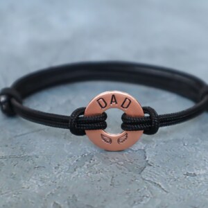 May include: Black paracord bracelet with a copper charm that says "DAD" with angel wings.