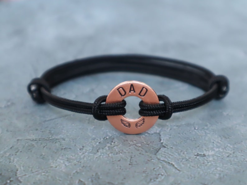 May include: Black paracord bracelet with a copper charm that says "DAD" with angel wings.