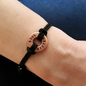 May include: A black cord bracelet with a copper charm that reads "Soul Sister".