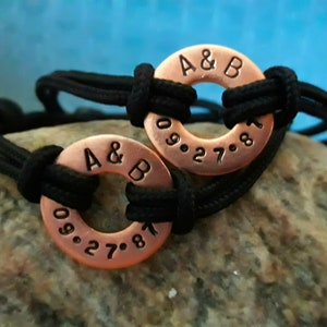 May include: Two matching copper bracelets with black cord. The bracelets have the initials "A & B" and the date "09.27.81" engraved on them.