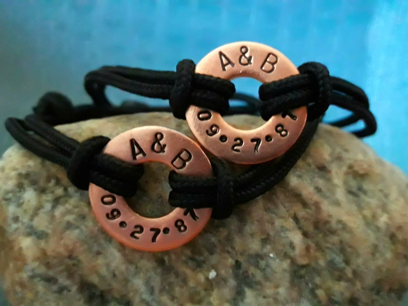 May include: Two matching copper bracelets with black cord. The bracelets have the initials "A & B" and the date "09.27.81" engraved on them.