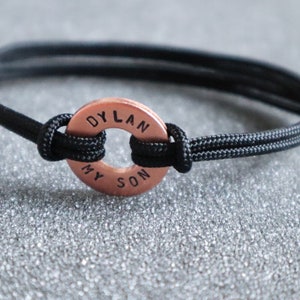 May include: A black paracord bracelet with a copper round charm that says "DYLAN MY SON".