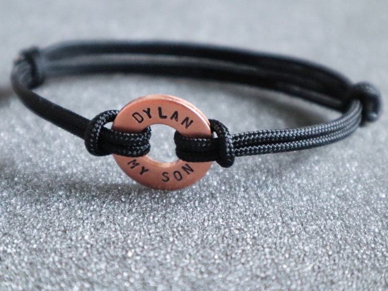 May include: A black paracord bracelet with a copper round charm that says "DYLAN MY SON".
