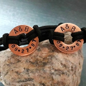 May include: Two copper bracelets with black cord. The bracelets have the initials "A & B" and the date "09.27.87" engraved on them.