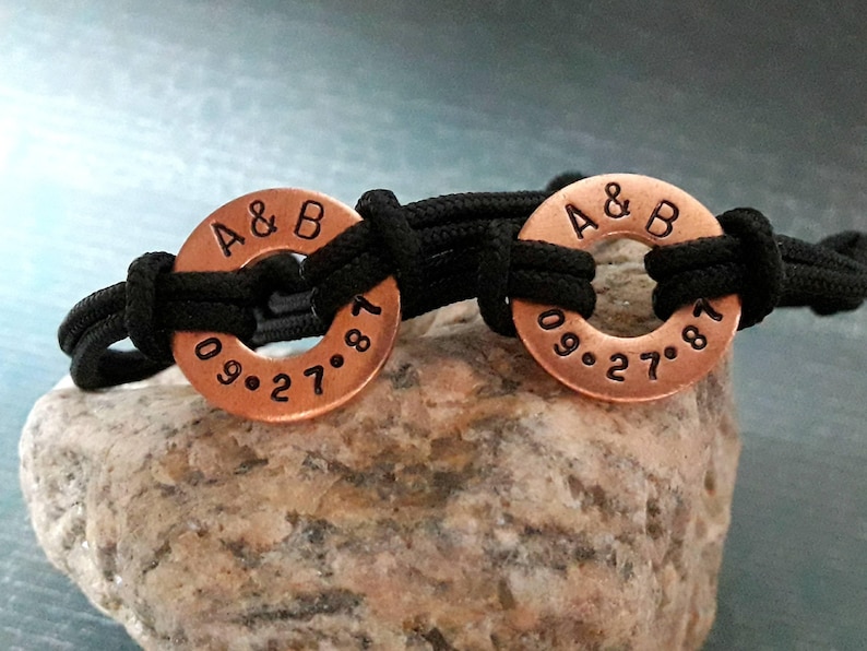 May include: Two copper bracelets with black cord. The bracelets have the initials "A & B" and the date "09.27.87" engraved on them.