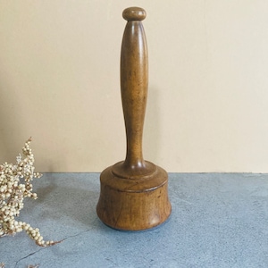 Könnte beinhalten: Ein Holzhammer mit einem runden Kopf und einem langen, zylindrischen Stiel. Der Hammer ist aus dunkelbraunem Holz gefertigt und hat eine glatte Oberfläche.