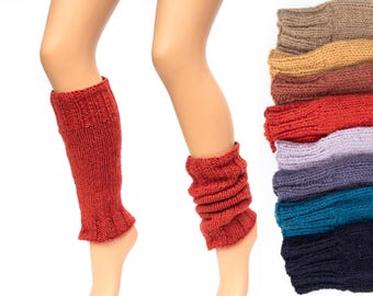May include: A pair of red knitted leg warmers on a model's legs. A stack of leg warmers in various colors is shown to the right of the model.