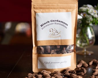 May include: A brown paper bag with a white label that reads "Black Cardamom Schwarzer Kardamom" and "Drentwelt". The bag contains black cardamom pods and has a white label on the bottom that reads "Nepali premium quality".