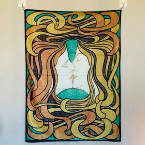 Front view of Peter Behrens The Kiss wall tapestry with intertwined profiles and sweeping yellow, orange, green and black linework.