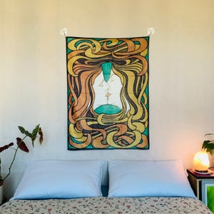 A colorful wall tapestry serving as room decor tapestry lesbian aesthetic, hung centrally over a bed with white pillows. The vintage fabric poster radiates warmth with its golden, green, and orange symmetrical kissing figures.