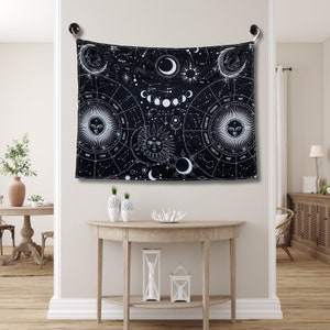 Black and white celestial tapestry displayed above a console table, with zodiac symbols, moon phases, constellations, and sun moon artwork.