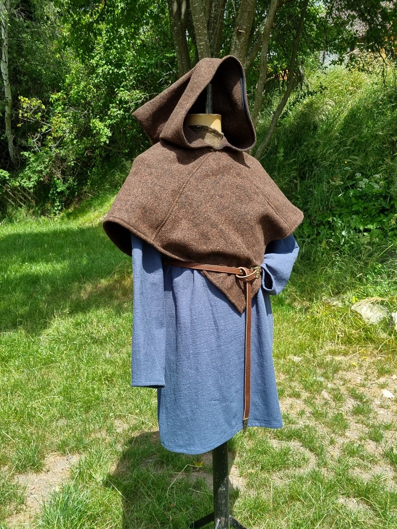 May include: A brown hooded cloak with a leather belt. The cloak is made of a thick, woven fabric and has a simple, functional design.