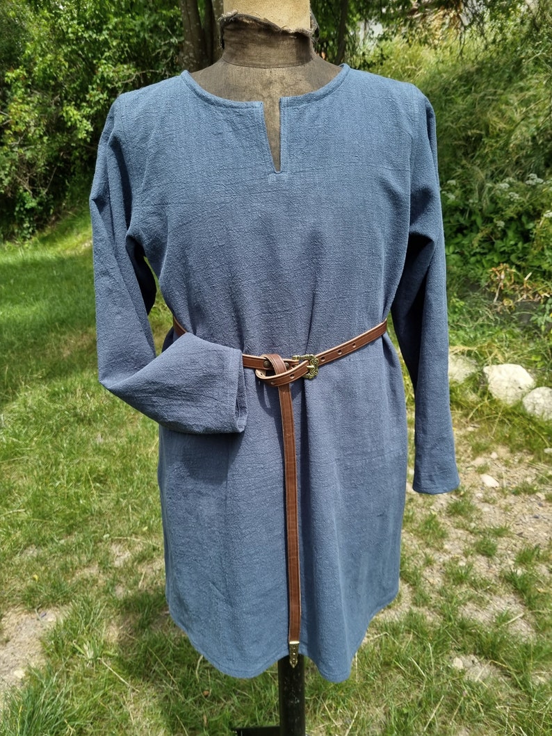 May include: A long-sleeved, blue tunic with a V-neck and a brown leather belt.