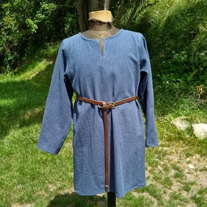 May include: A long-sleeved, blue tunic with a V-neck and a brown leather belt.