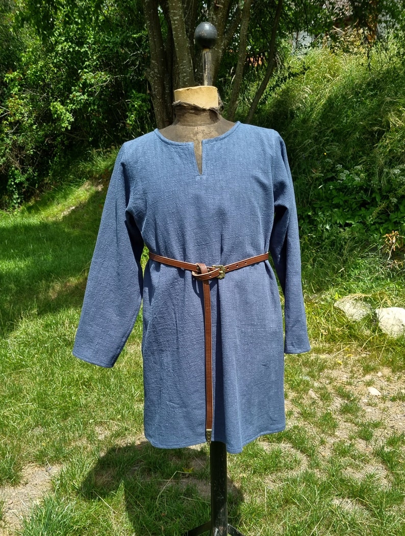 May include: A long-sleeved, blue tunic with a V-neck and a brown leather belt.