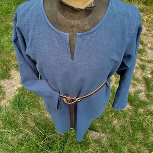 May include: A long-sleeved, blue tunic with a V-neck and a brown leather belt.