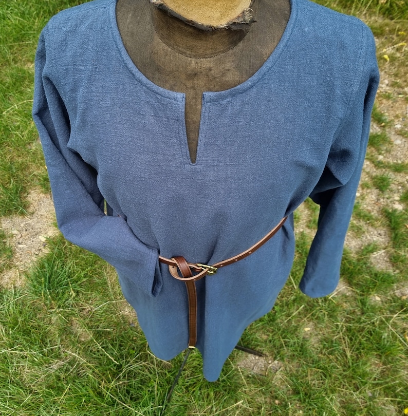 May include: A long-sleeved, blue tunic with a V-neck and a brown leather belt.