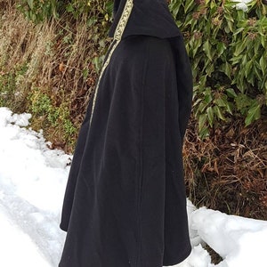 May include: A black hooded cloak with a gold trim. The cloak is made of a soft, warm fabric and has a long, flowing design. The hood is lined with a soft, comfortable fabric.