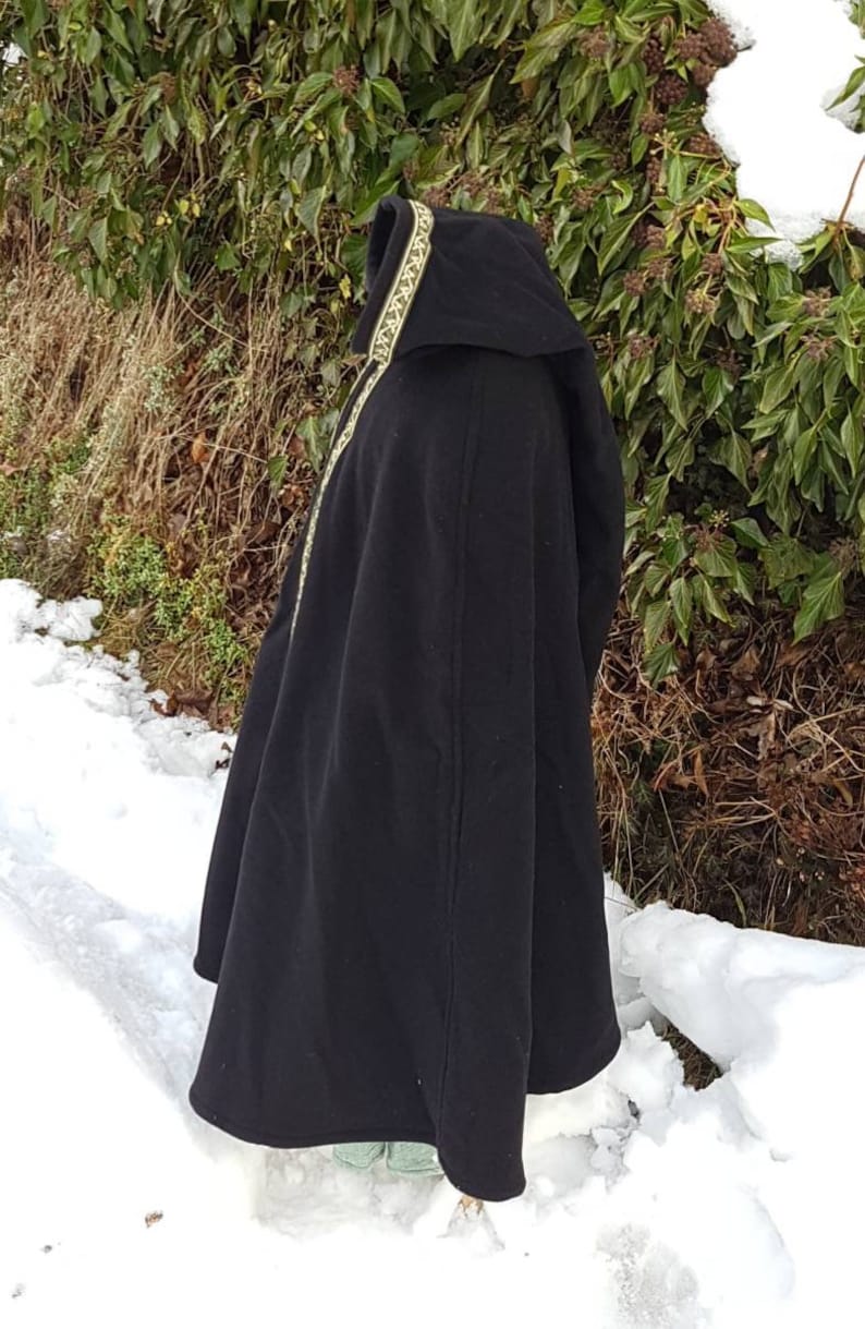May include: A black hooded cloak with a gold trim. The cloak is made of a soft, warm fabric and has a long, flowing design. The hood is lined with a soft, comfortable fabric.